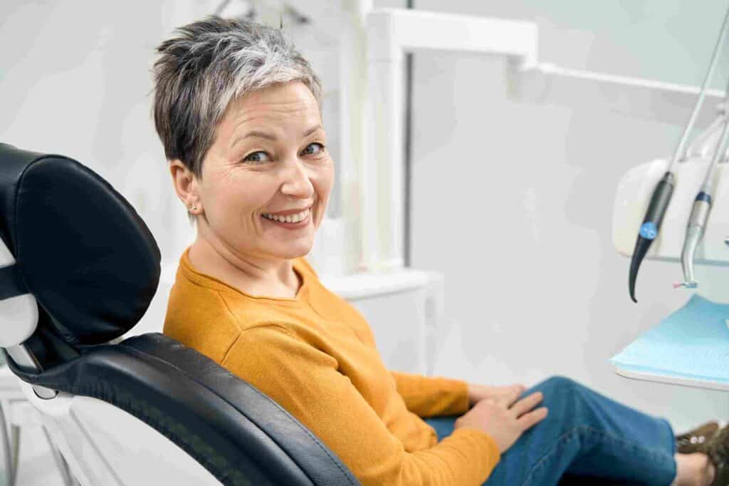 Smiling patient sitting in a modern dental clinic in Irvine, CA after a friendly dental visit